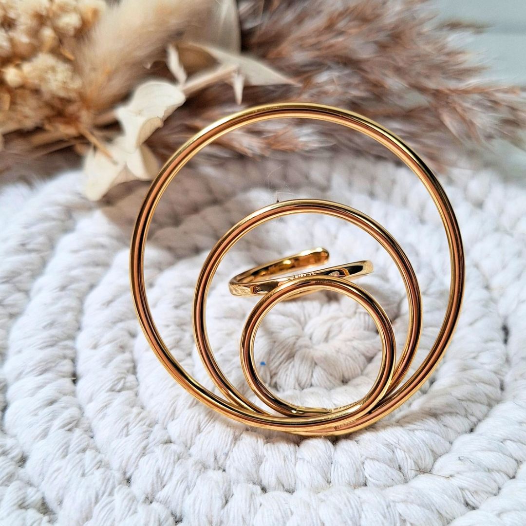 Bague spirale dorée XXL en acier inoxydable posée sur fond clair
