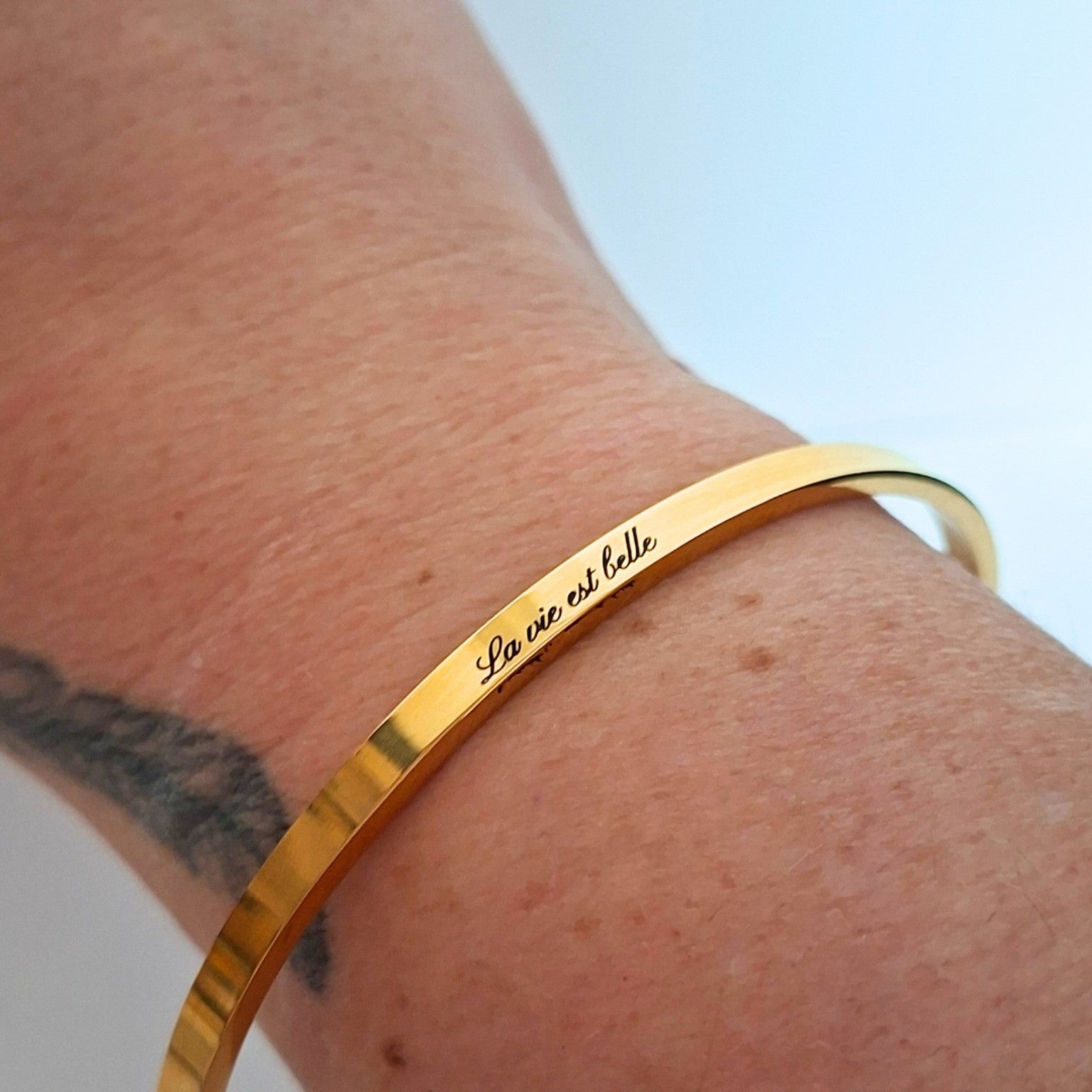 Bracelet doré gravé La vie est belle porté au poignet