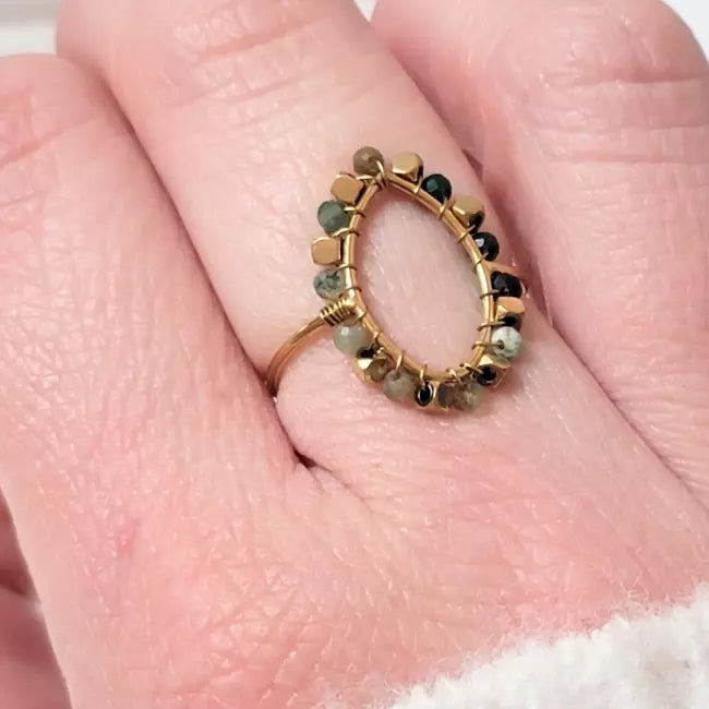 Bague dorée ajustable en acier inoxydable, forme amande décorée de perles, portée au doigt d’une femme