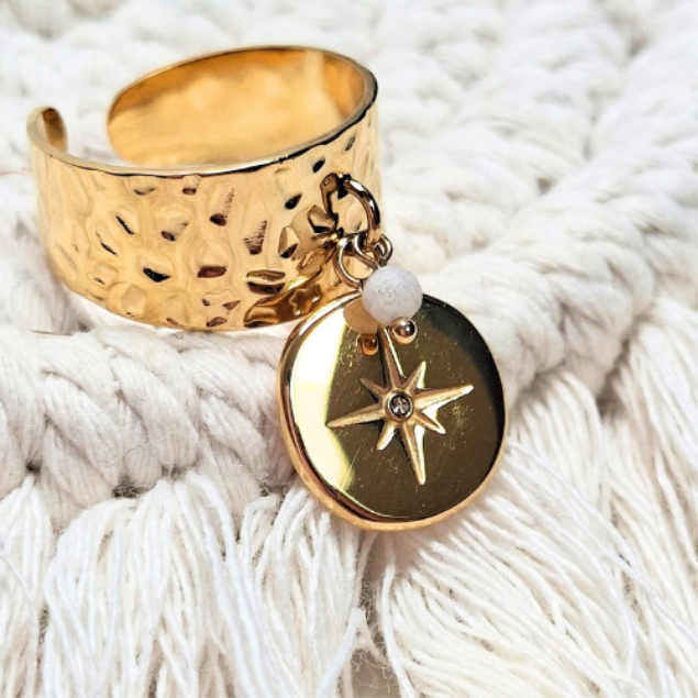 Gros plan pendentif étoile dorée sur cercle noir monté sur anneau martelé