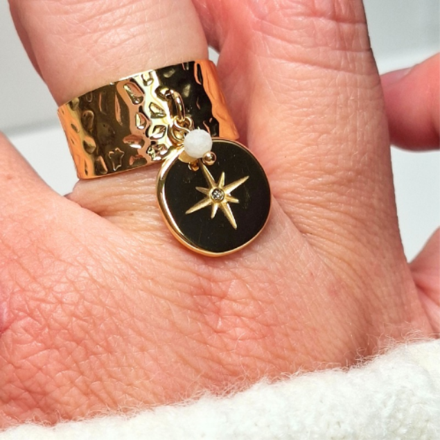 Bague en acier doré martelé avec pendentif étoile et perle blanche portée au doigt
