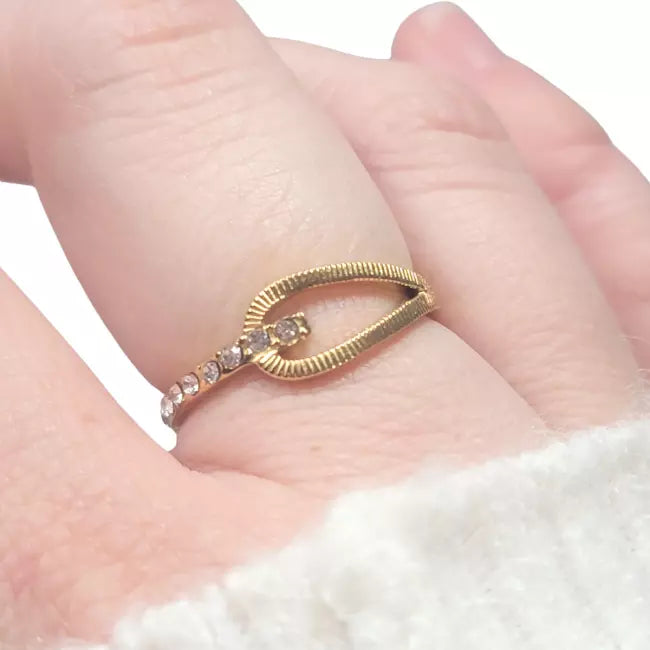Bague dorée ajustable portée au doigt avec strass scintillants