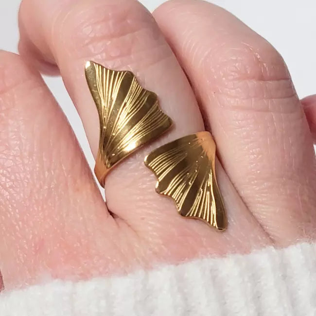 Bague ajustable dorée en acier inoxydable, design feuille de ginkgo biloba, portée au doigt d’une femme
