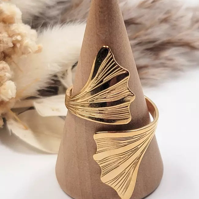 Bague dorée en acier inoxydable, inspiration nature avec double feuille de ginkgo, présentée sur support