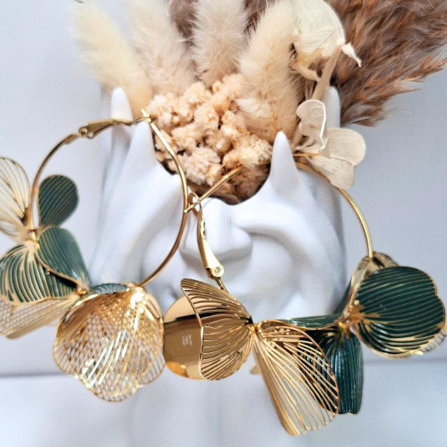 Créoles dorées ornées de fleurs dorées et vertes sur fond clair