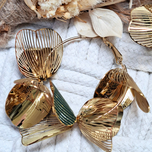 Gros plan sur pétales ajourés dorés et verts des boucles d’oreilles Belatika