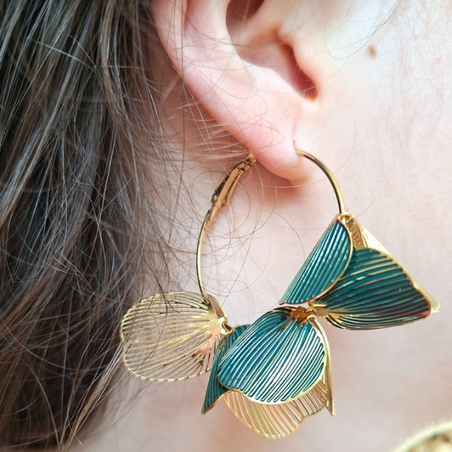 Boucles d’oreilles créoles dorées avec fleurs ajourées vert et or portées à l’oreille