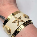 Bracelet manchette large beige avec étoile de mer et coquillages dorés