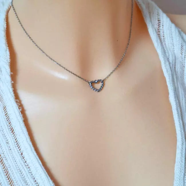 Collier cœur torsadé argenté porté, pendentif ajouré avec petit strass sur fine chaîne.