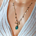 Collier doré en acier inoxydable porté, pendentif vert marbré ovale et chaîne à pampilles, fermoir toggle chic.