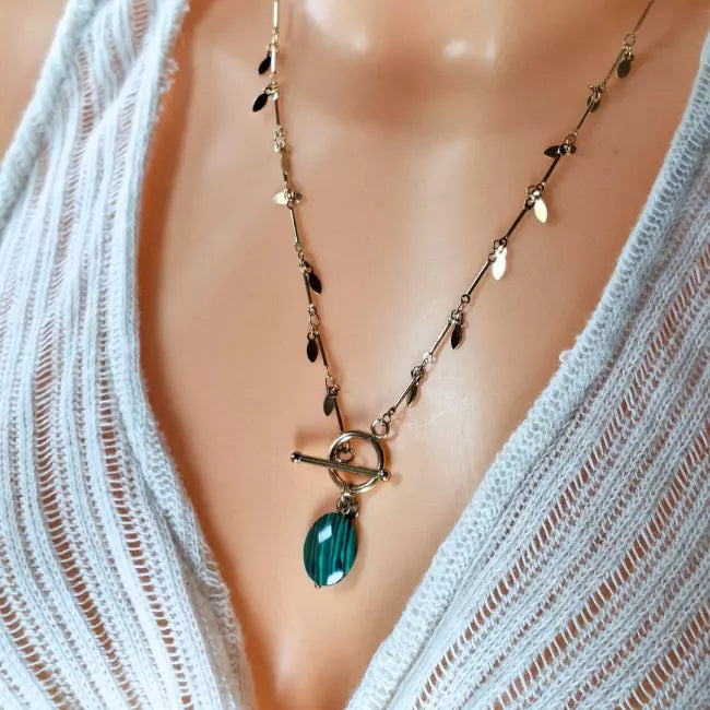 Collier doré en acier inoxydable porté, pendentif vert marbré ovale et chaîne à pampilles, fermoir toggle chic.