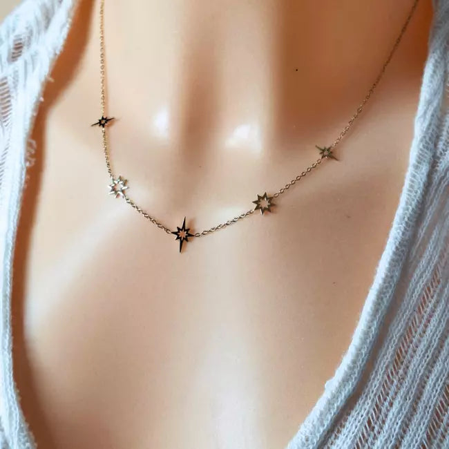 Collier doré en acier inoxydable porté, pendentifs étoiles du nord ajourées réparties sur une fine chaîne.