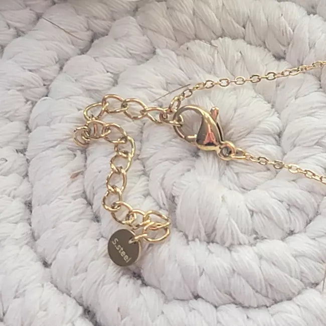 Détail du fermoir mousqueton doré et chaînette d’extension du collier étoile du nord, gros plan.