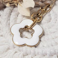 Collier fleur blanc en acrylique avec contour doré, pendentif accroché à une chaîne dorée à gros maillons.