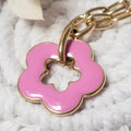 Collier fleur rose en acrylique avec contour doré, pendentif sur chaîne dorée à gros maillons, gros plan.