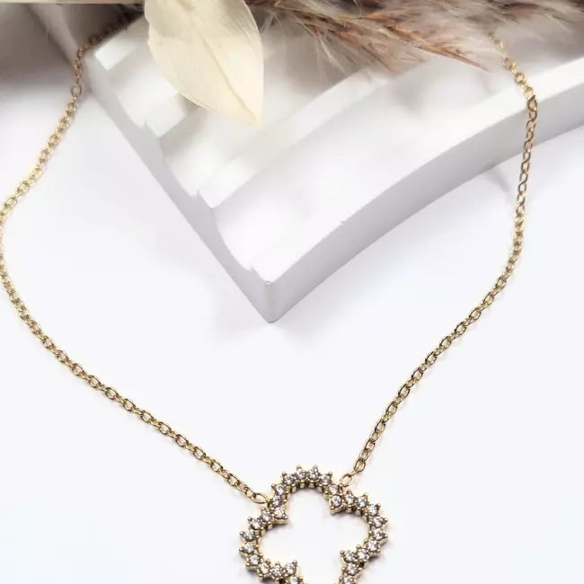 Collier fleur doré en acier inoxydable, pendentif ajouré orné de strass, sur fond blanc avec fleurs séchées.