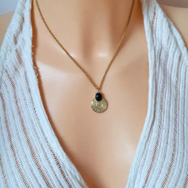 Collier pendentif doré porté – chaîne fine et médaillon rond texturé avec cabochon bleu pailleté, aperçu de la longueur sur le décolleté.