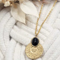 Collier pendentif doré en acier inoxydable avec cabochon bleu pailleté, médaillon rond texturé – gros plan sur fond corde blanche.