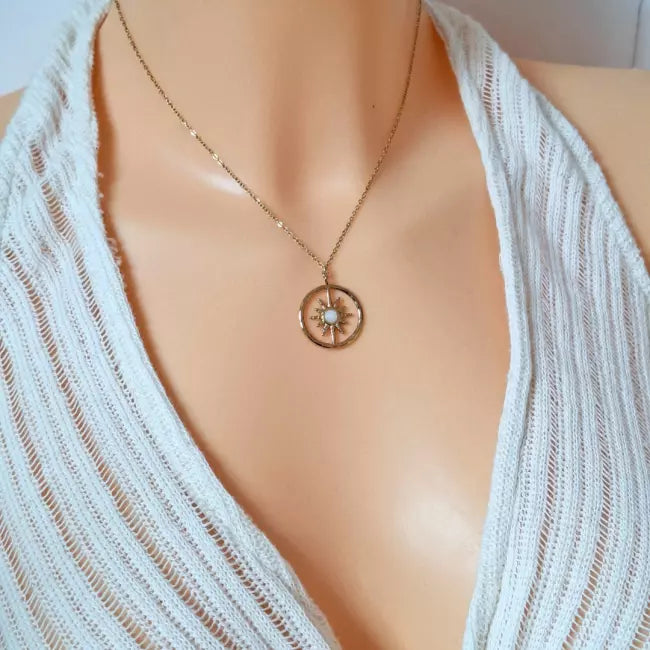 Collier soleil doré femme porté, pendentif rond avec pierre blanche centrale, style chic.