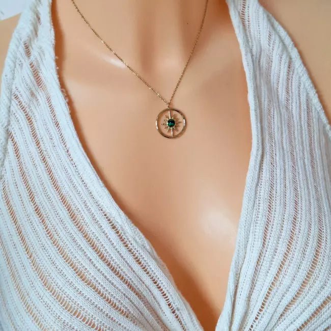 Collier soleil doré porté, pendentif rond avec pierre verte centrale, chaîne fine en acier inoxydable.